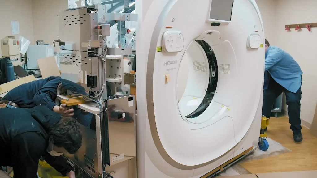 Technicians installing a Hitachi Scenaria View CT scanner at Stewart Memorial Hospital, with the gantry cover open