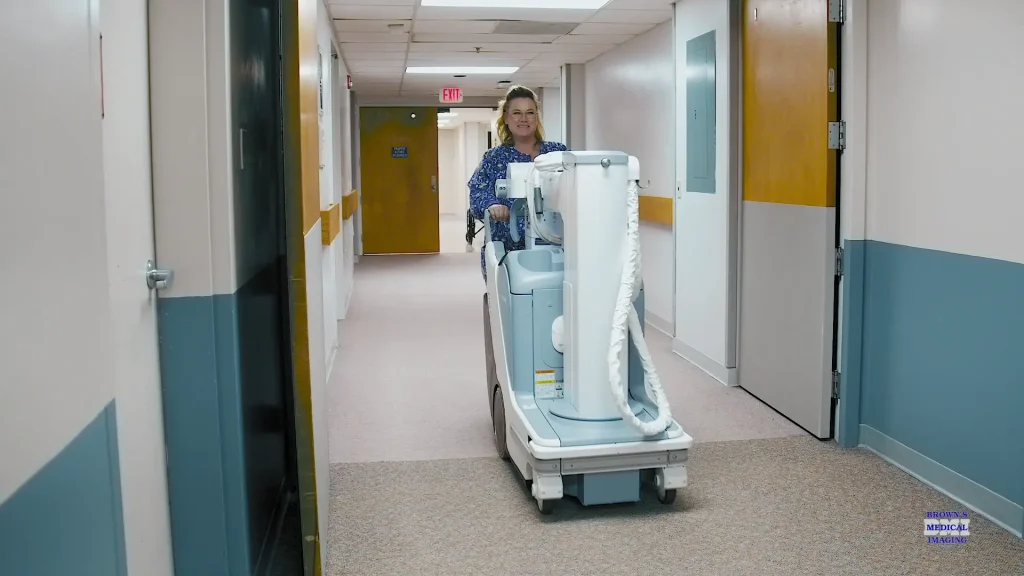 Technologist pushing a portable X-ray unit down a hospital hallway at Decatur Health