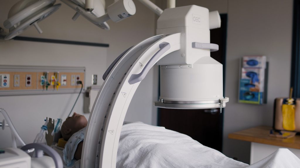 GE OEC mobile C-arm imaging system positioned over a patient in a hospital bed