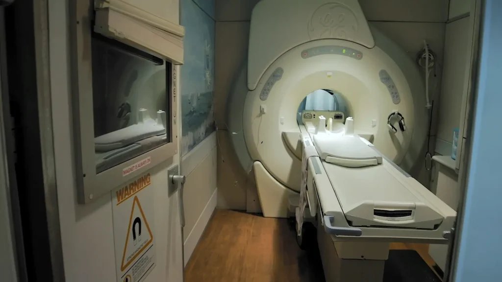 GE MRI scanner in a veterinary imaging suite with patient table extended and magnet warning signage on the door