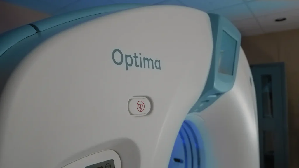 Close-up of a GE Optima CT scanner gantry showing the Optima nameplate and control panel