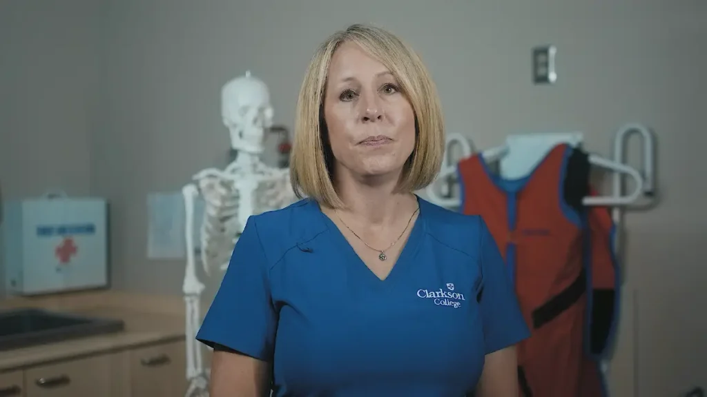 Clarkson College radiologic technology student standing in an exam room with an anatomical skeleton model in the background