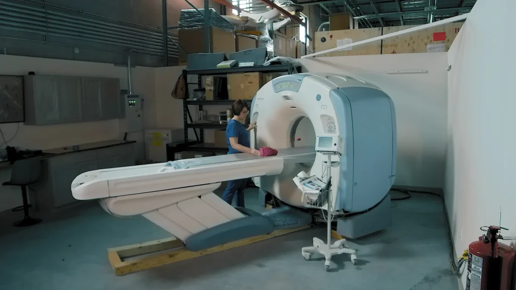Technologist working on a CT scanner gantry during installation in a warehouse setting
