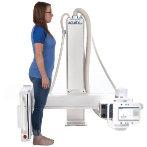 Woman standing sideways at the Acuity SDR+ upright radiography system for a lateral X-ray