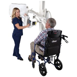 Radiologic technologist positioning a seated wheelchair patient for an X-ray exam using the Essentia SA's overhead tube head
