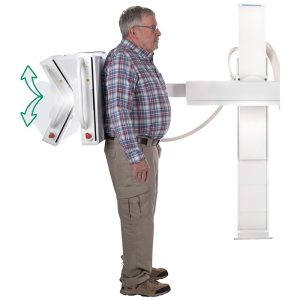 Side view of a patient standing against the Essentia SA's upright wall stand detector for a chest X-ray, with green arrows indicating vertical detector movement
