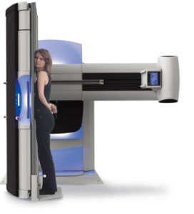 Illustration of a patient standing at the Persona RF PREMIUM wall stand for native chest imaging, with the table and tube arm in the background
