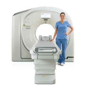 Female technologist standing beside the Fujifilm SCENARIA View Focus Edition CT scanner with the patient table extended
