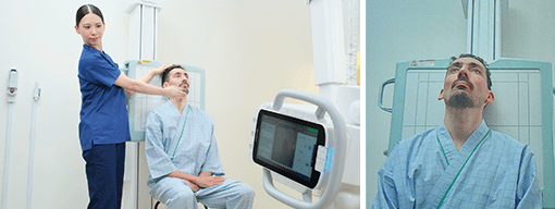 Technologist positioning a seated patient at the wall bucky stand on the RADspeed Pro SR5 system