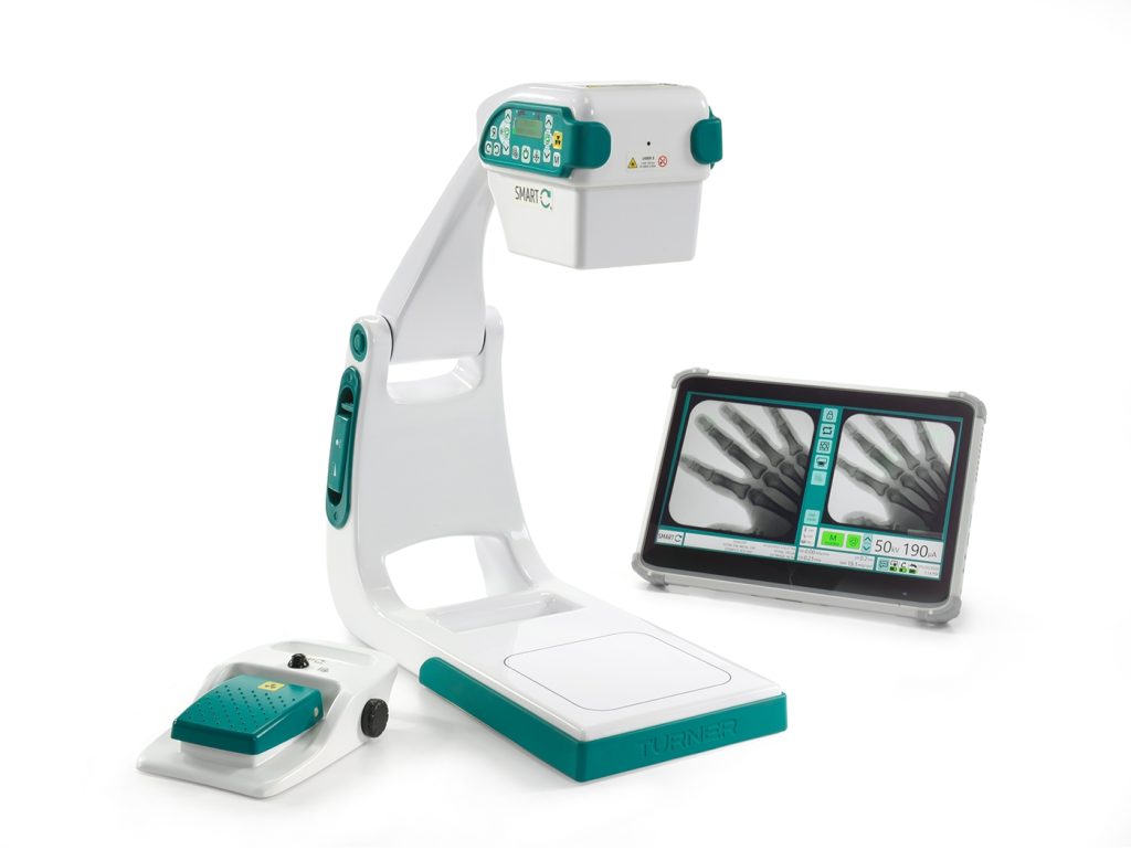 Technologist standing beside the Smart C mini C-arm fluoroscopy system with dual monitor cart