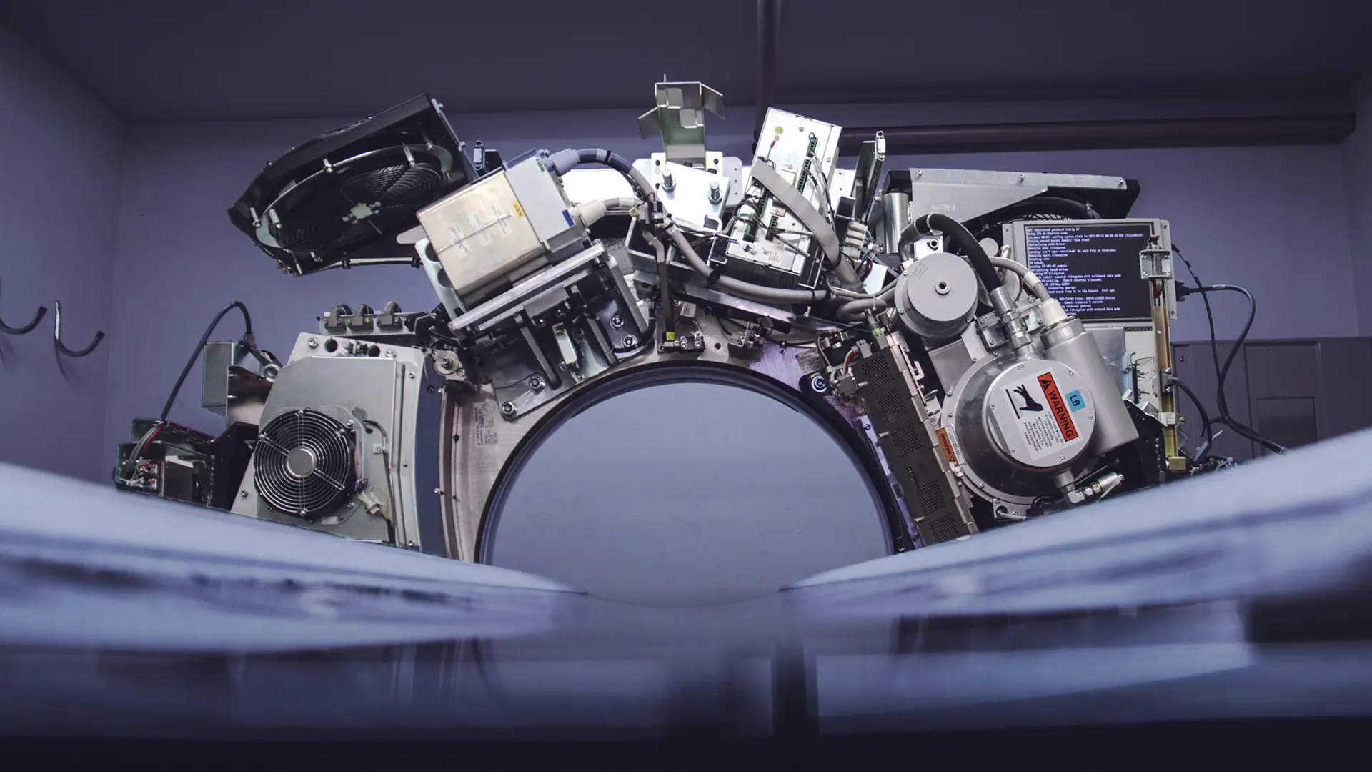 Close-up of open MRI/CT gantry internals showing wiring and circuit boards
