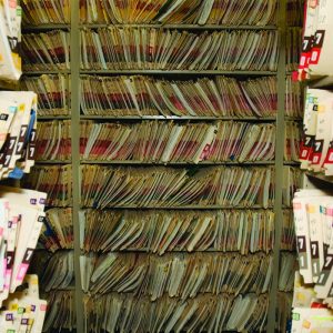 Rows of overstuffed medical record file folders on shelving in a records storage room