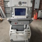 Agfa DR 100s mobile X-ray unit, front view showing tube head, monitor, and control panel in warehouse