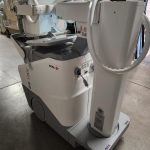 Agfa DR 100s mobile X-ray unit, angled rear view showing tube column and wheeled base in warehouse