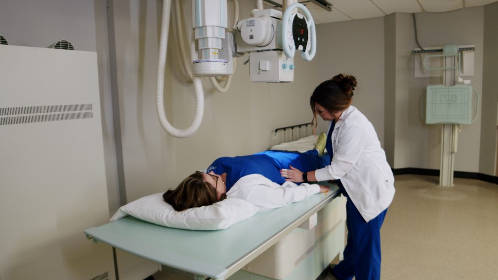 Technologist positioning a patient's pelvis on an X-ray table for an AP pelvis X-ray