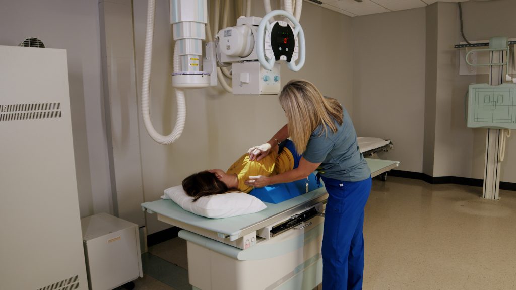 Technologist positioning a patient's shoulder on an X-ray table for a scapular Y trauma series