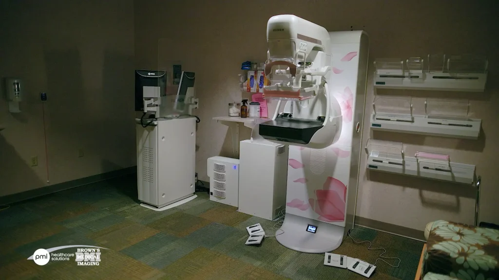 Fujifilm mammography system in a dimly lit exam room with a floral pink design on the housing