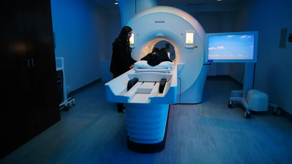 Video thumbnail showing a technologist and patient using a Fujifilm MRI scanner in a blue-lit exam room, Full Site Overview