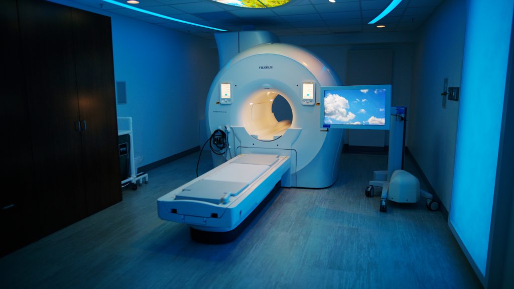 Fujifilm MRI scanner in a blue-lit exam room with a cloud-display monitor for patient comfort