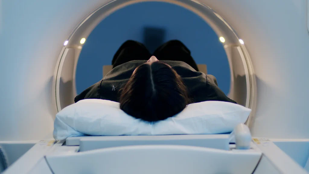 Overhead view of a patient's head entering an MRI scanner bore, video thumbnail for a One Point of Contact article