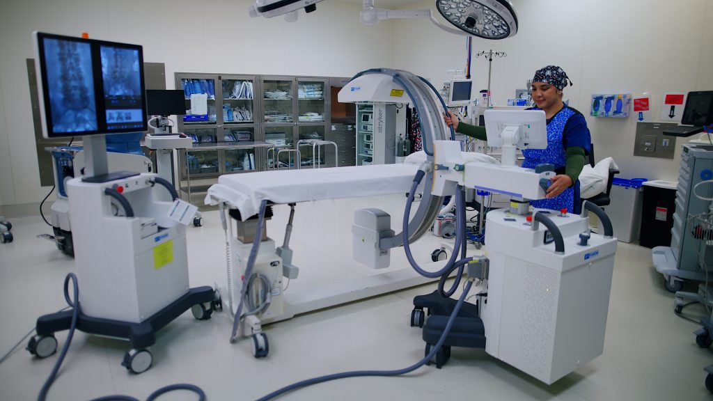 Technologist operating an XR Fusion mobile C-arm system in an operating room