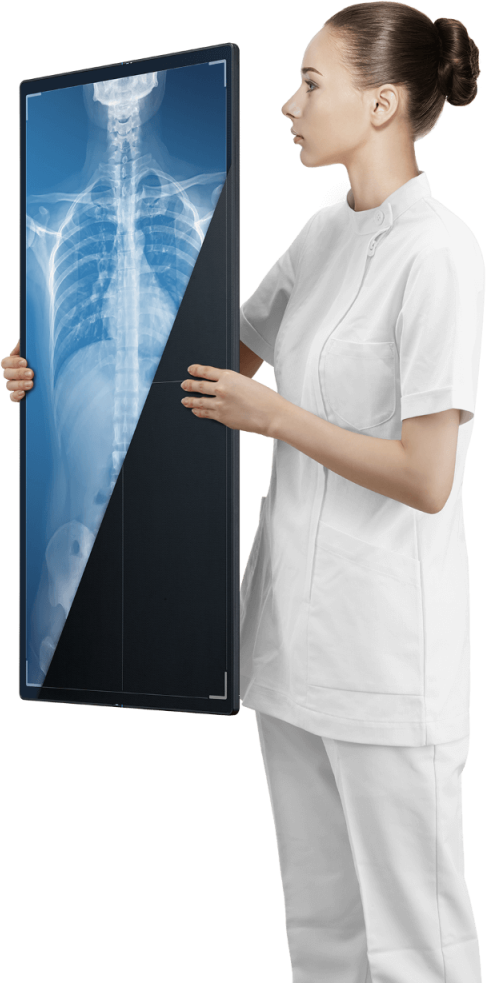 Technologist holding a Fujifilm wireless flat panel detector displaying a spine X-ray image