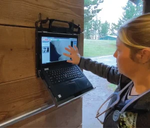 Veterinarian viewing an X-ray image on a laptop mounted to a barn wall
